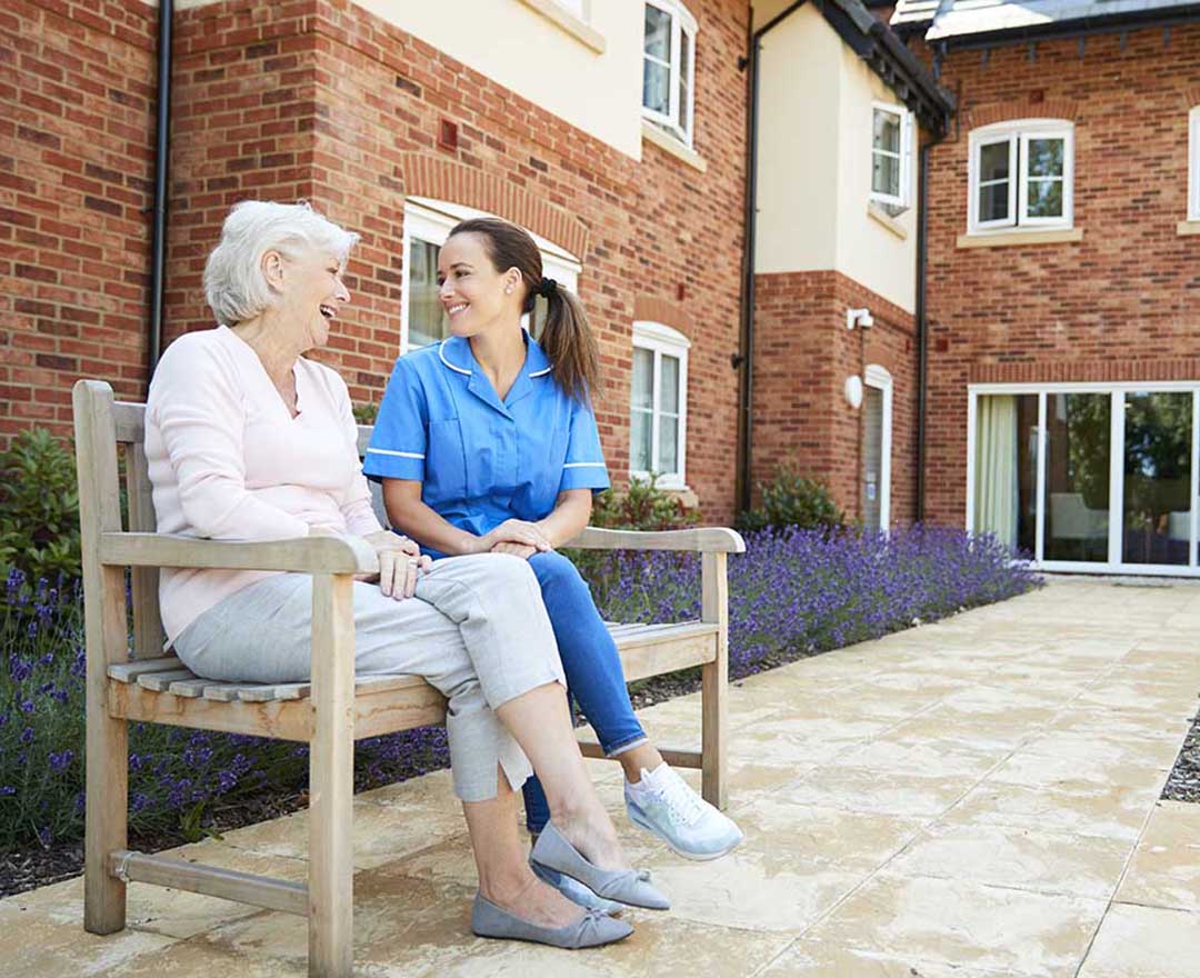 A caregiver sharing a warm, attentive moment with an older adult client at home.